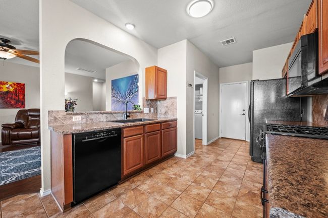 Views of the sleek tile backsplash and a conveniently placed laundry room. | Image 8