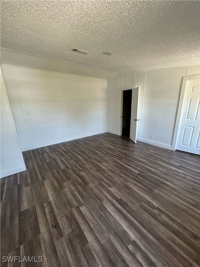 Spare room with dark wood-style flooring, a textured ceiling, visible vents, and baseboards | Image 11