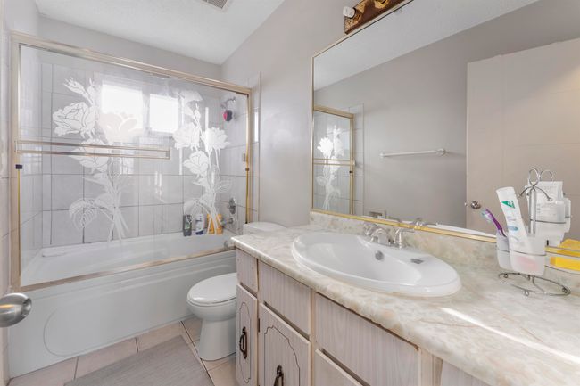 Full bathroom featuring toilet, tile patterned floors, vanity, and shower / bath combination with glass door | Image 19