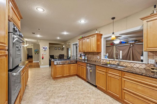 Kitchen featuring a peninsula, a sink, recessed lighting, backsplash, and appliances with stainless steel finishes | Image 10