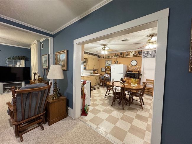 Dining space with ornamental molding, ceiling fan, a textured ceiling, and light flooring | Image 11