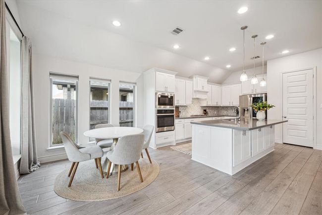 Bathed in natural light from surrounding windows, the bright breakfast area connects seamlessly with the kitchen and living room, offering a serene spot to start your mornings while enjoying peaceful views. | Image 14