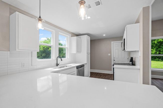 Kitchen featuring appliances with stainless steel finishes, tasteful backsplash, dark wood-style floors, white cabinetry, and recessed lighting | Image 4