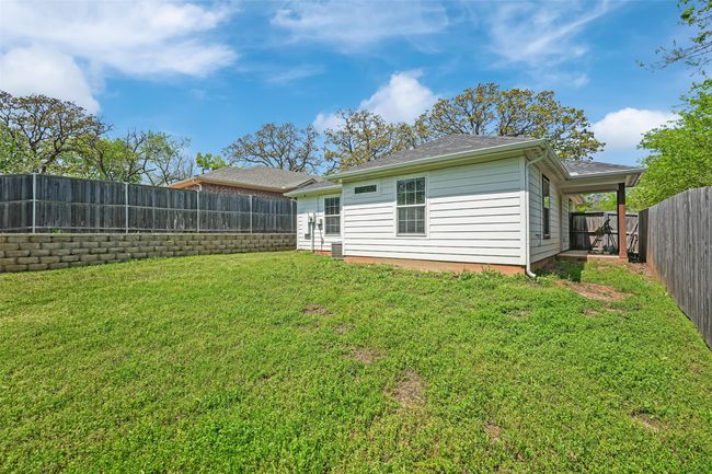 Rear view of house featuring a fenced backyard, a shingled roof, and a lawn | Image 31