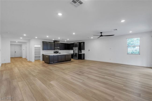 Kitchen featuring open floor plan, stainless steel appliances, light countertops, recessed lighting, and a center island with sink | Image 7