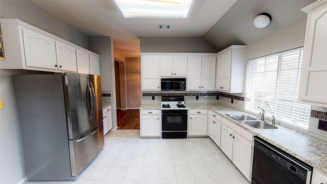 Kitchen featuring black appliances, white cabinetry, tasteful backsplash, and vaulted ceiling | Image 4
