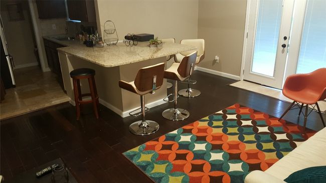 Kitchen featuring decorative backsplash, baseboards, a kitchen bar, dark wood finished floors, and a sink | Image 27
