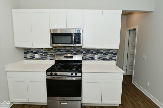 kitchen with tasteful backsplash, appliances with stainless steel finishes, and white cabinets | Image 13