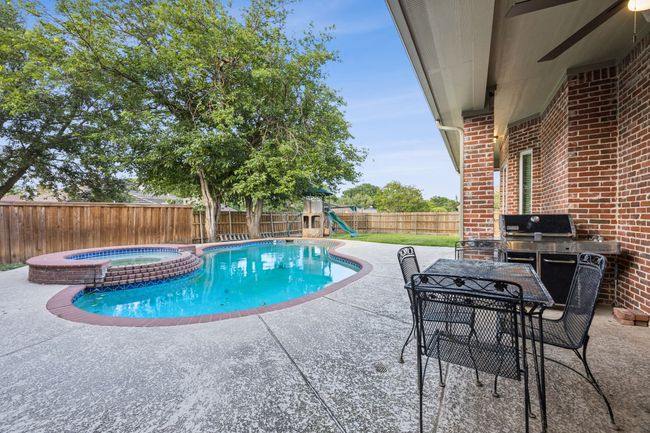 View of pool with a large fenced backyard, a covered patio, a pool with connected hot tub, and grilling area | Image 26