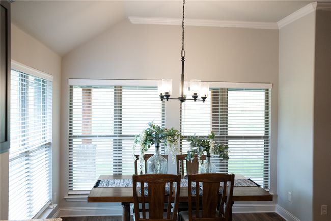 Dining area featuring wood finished floors, a chandelier, vaulted ceiling, baseboards, and crown molding | Image 11