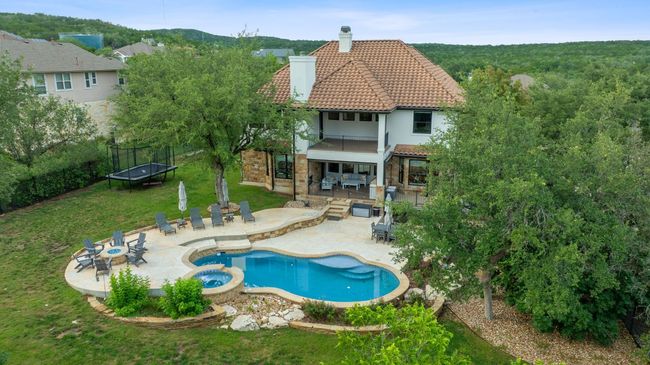 Rear view of house featuring a trampoline, a tiled roof, a chimney, a patio, and a balcony | Image 33