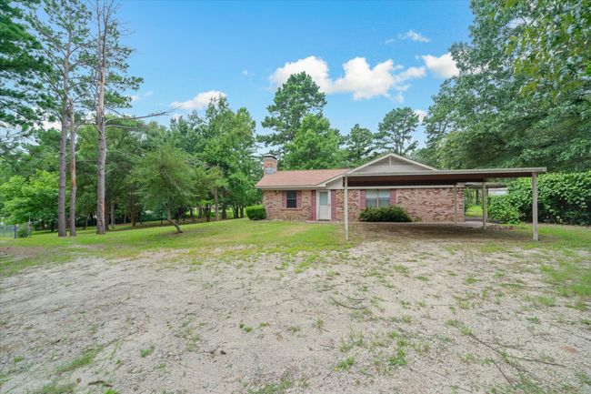 View of front facade with a chimney, brick siding, a front yard, and a detached carport | Image 35