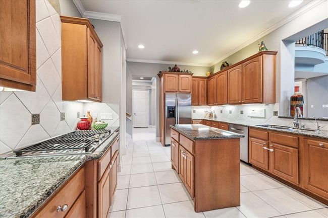 The Chef's Kitchen features an island, double ovens, warmer & breakfast bar seating. Outlets are hidden underneath the cabinets, leaving the elegant backsplash uninterrupted. Fridge STAYS! | Image 10