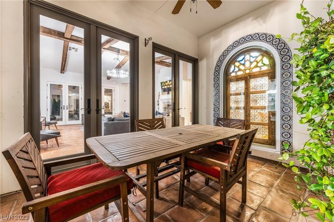 Outdoor dining in the loggia, double french doors to the living room, ceiling fan and decorative window into the office. | Image 18