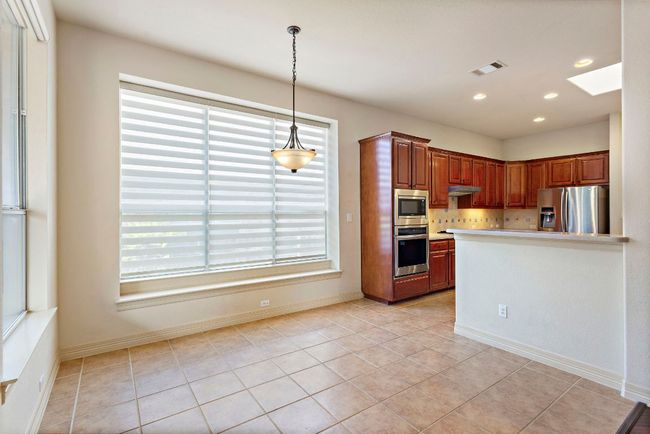 Kitchen with hanging light fixtures, a skylight, appliances with stainless steel finishes, under cabinet range hood, and visible vents | Image 14