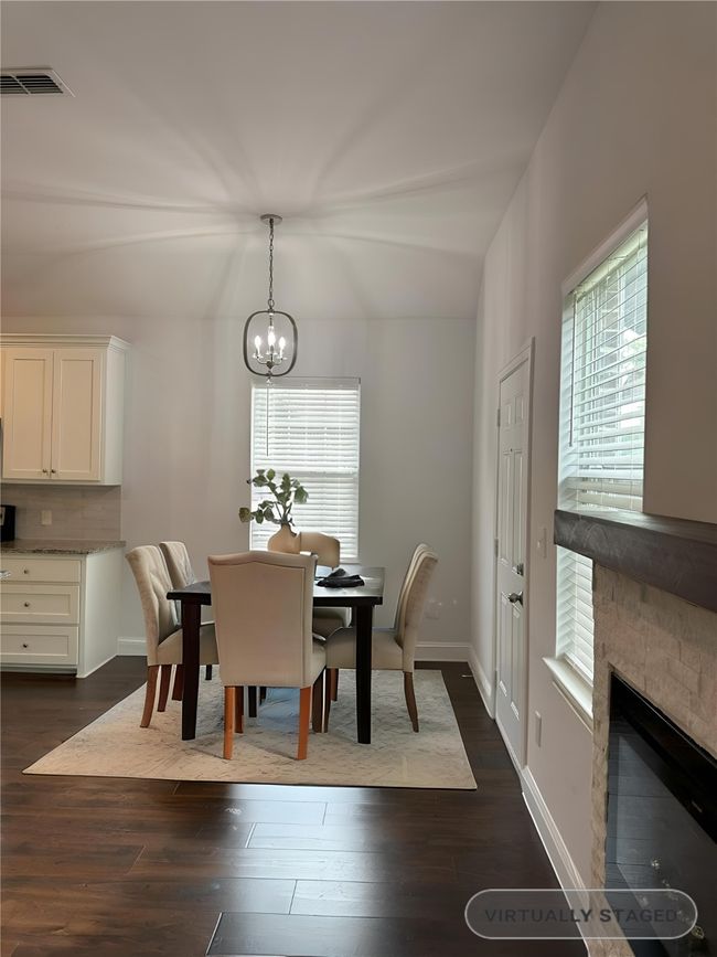 Staged Dining area featuring a chandelier, dark wood-type flooring, and a stone fireplace | Image 11