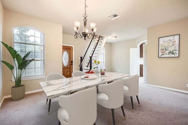 Dining room with light carpet, a chandelier, stairway, and baseboards | Image 6