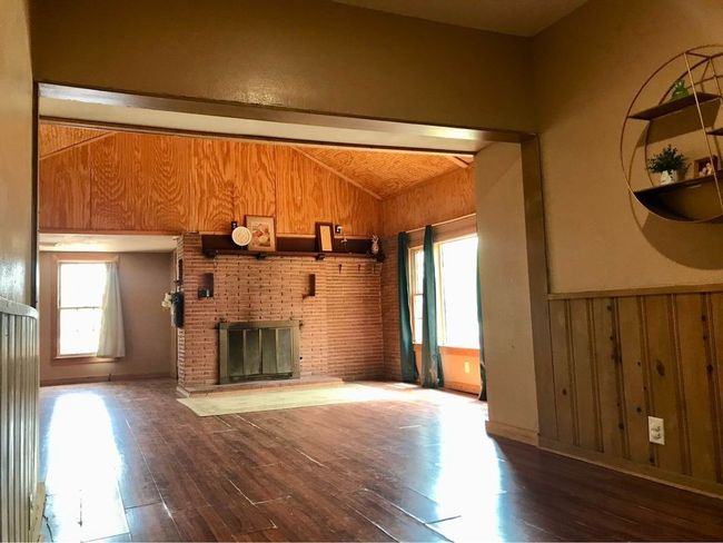 Unfurnished living room featuring hardwood / wood-style floors, a fireplace, vaulted ceiling, and a wealth of natural light | Image 8