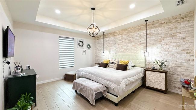 Bedroom featuring brick wall, light wood-style floors, a raised ceiling, and recessed lighting | Image 10