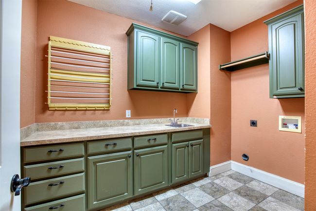 Laundry room featuring cabinetry, counter, sink, and built-in dyer rack. | Image 22