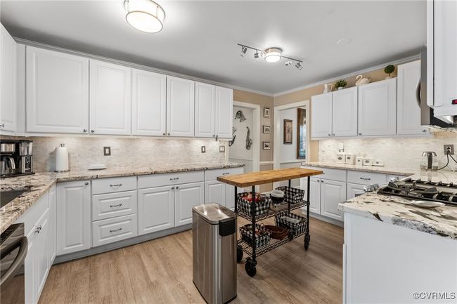 Kitchen with dishwasher, light wood-type flooring, white cabinetry, and ornamental molding | Image 15