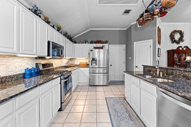 Kitchen featuring lofted ceiling, sink, stainless steel appliances, and white cabinets | Image 12