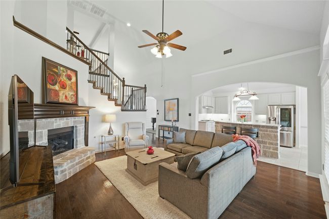 Living area with arched walkways, dark wood-style floors, high vaulted ceiling, ceiling fan, and a stone fireplace | Image 19