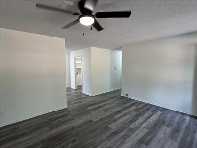 Empty room with a textured ceiling, ceiling fan, and dark hardwood / wood-style flooring | Image 3