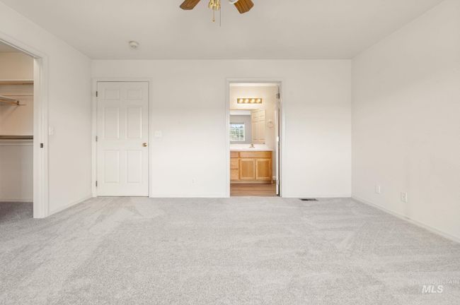 Unfurnished bedroom featuring a walk in closet, carpet floors, a closet, a ceiling fan, and ensuite bath | Image 19