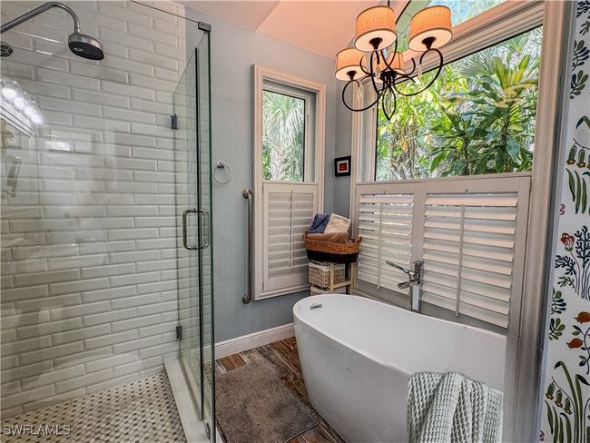 Bathroom featuring a shower stall, baseboards, a freestanding tub, and an inviting chandelier | Image 13