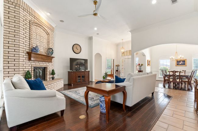Arched walkways surround the formal dining room with wood flooring & a gorgeous chandelier. | Image 7