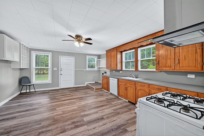 Kitchen featuring white appliances, healthy amount of natural light, a ceiling fan, and light wood-style flooring | Image 8
