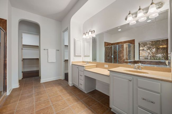 Bathroom with baseboards, tile patterned flooring, vanity, a walk in closet, and a stall shower | Image 22