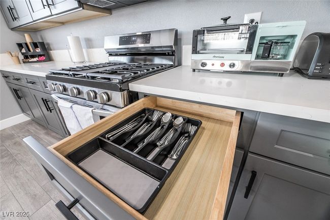 Kitchen with stainless steel gas stove, light countertops, light wood-style flooring, and gray cabinets | Image 13