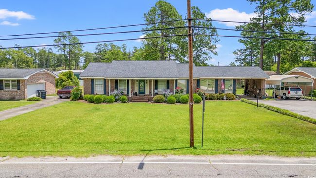 Ranch-style home with a porch, a carport, a front yard, and brick siding | Image 20