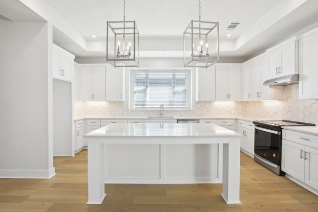 Kitchen with under cabinet range hood, visible vents, a tray ceiling, and stainless steel range with electric cooktop | Image 14