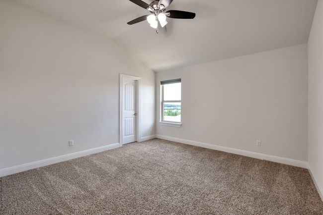 Empty room featuring carpet, a ceiling fan, and vaulted ceiling | Image 33