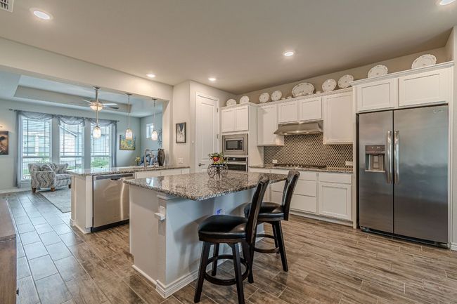 Kitchen featuring stainless steel appliances, range hood, dark wood-style floors, a peninsula, and recessed lighting | Image 14