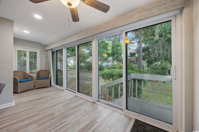 Unfurnished sunroom featuring ceiling fan, wood finished floors, recessed lighting, a deck, and lofted ceiling | Image 20
