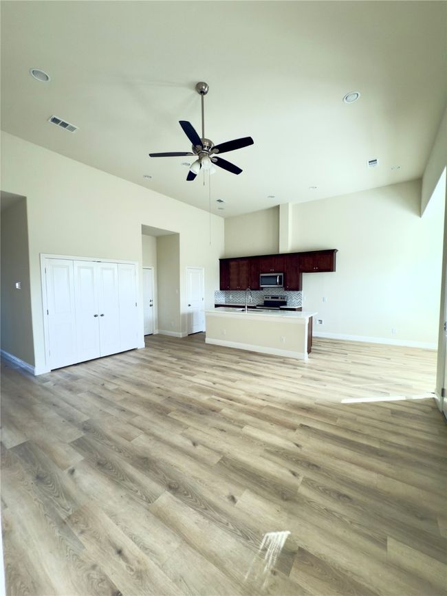 Unfurnished living room with baseboards, a ceiling fan, light wood finished floors, recessed lighting, and lofted ceiling | Image 13