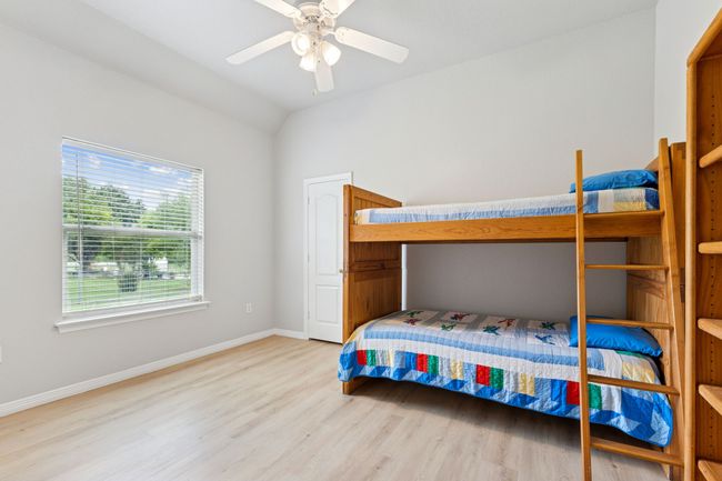 Bedroom with light wood-type flooring, baseboards, lofted ceiling, and ceiling fan | Image 24