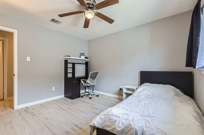 Bedroom with light wood-style floors, a textured ceiling, baseboards, and an office area | Image 19