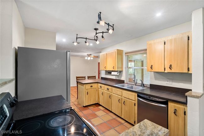 Kitchen with sink, light tile patterned floors, ceiling fan, stainless steel appliances, and kitchen peninsula | Image 10