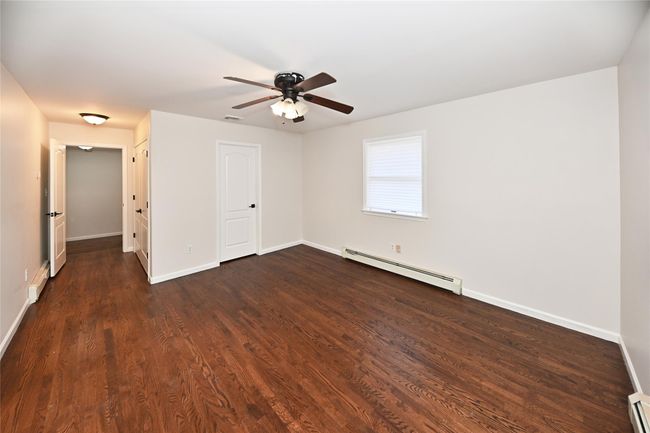 Spare room featuring baseboard heating, baseboards, a ceiling fan, and dark wood finished floors | Image 25