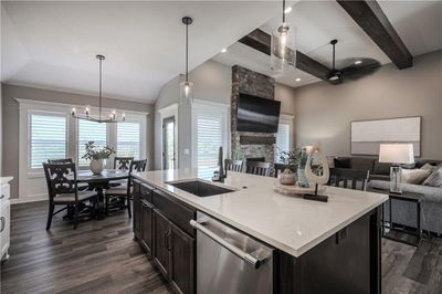 Kitchen featuring dark hardwood / wood-style floors, a fireplace, an island with sink, stainless steel dishwasher, and sink | Image 3