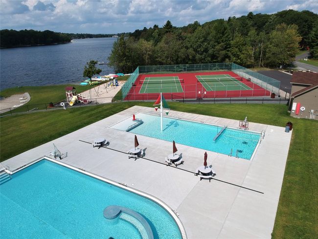 Pool featuring a tennis court, a water play area, fence, and a lawn | Image 5
