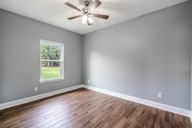 Spare room featuring wood finished floors, baseboards, and ceiling fan | Image 21