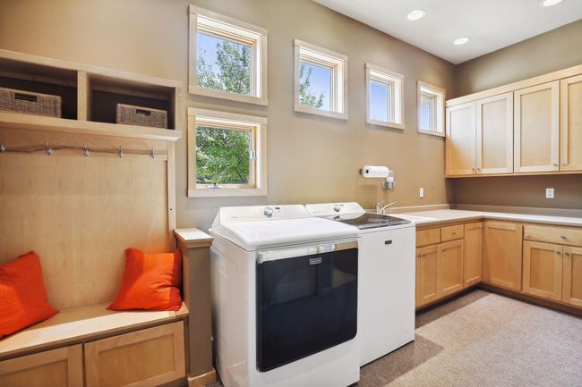 Custom built means fabulous, storage spaces and nooks! Check out this beautiful main floor mud room with laundry. Awesome window design brings natural light in. Abundance of custom cabinetry and storage!! Bench and hooks for all the extras! | Image 22