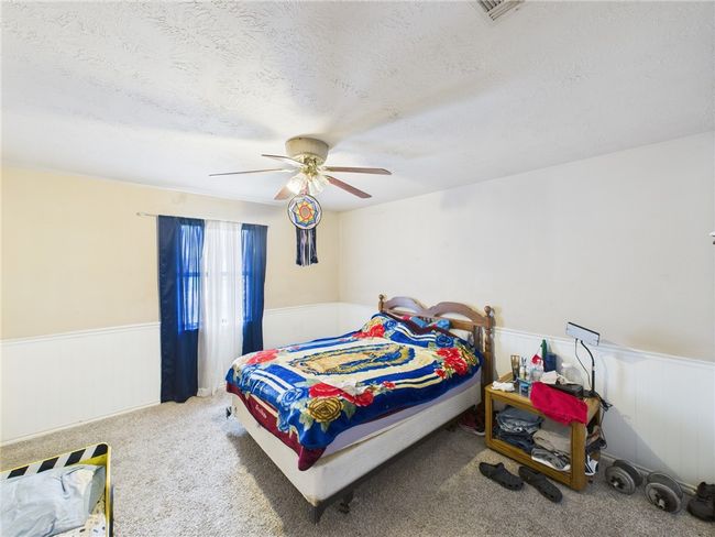 Carpeted bedroom with wainscoting, a textured ceiling, and ceiling fan | Image 8