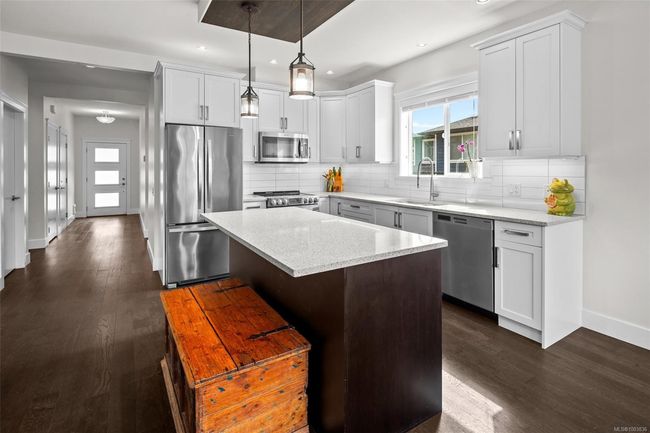 Kitchen featuring stainless steel appliances, recessed lighting, dark wood-style floors, a kitchen island, and tasteful backsplash | Image 14